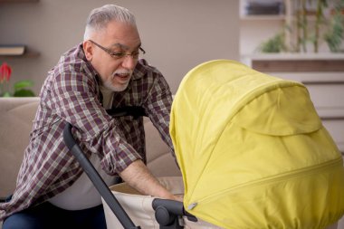 Old man looking after baby at home