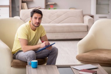 Genç erkek öğrenci salgın sırasında evden çalışıyor.