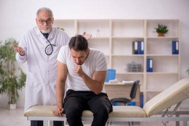 Genç hasta yaşlı erkek doktoru ziyaret ediyor.