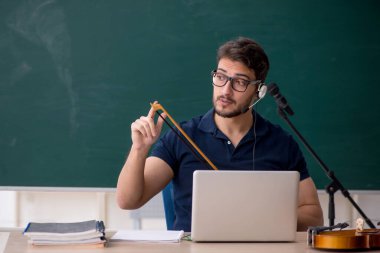 Sınıfta oturan genç müzik öğretmeni.