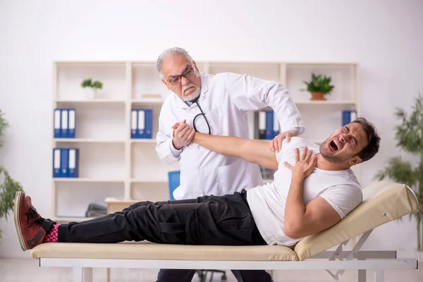 Young doctor visiting old doctor chiropractor
