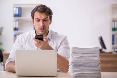 Genç işadamı ve işyerinde çok fazla iş var.