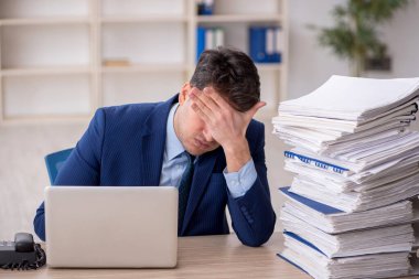 Young employee and too much work at workplace