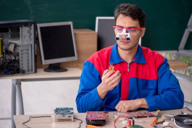 Sınıfta bilgisayar tamir eden genç bir tamirci.