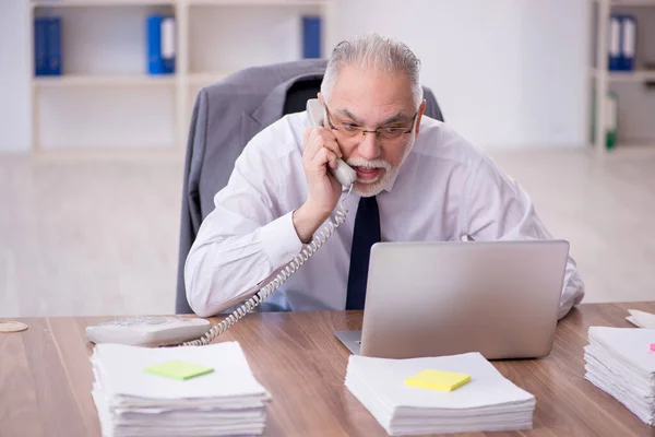 Old businessman employee unhappy with excessive work at workplace