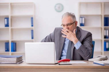 Old employee sitting at workplace