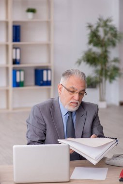 Old employee sitting at workplace