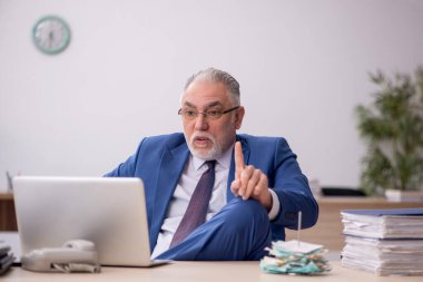 Old employee sitting at workplace