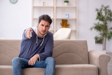 Evde televizyon izleyen genç bir erkek öğrenci.