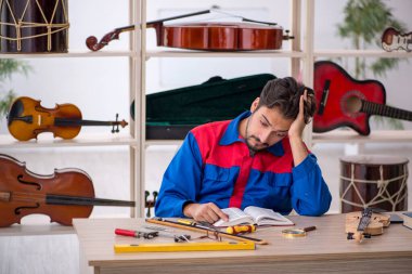 İçeride müzik aletlerini tamir eden genç bir adam.