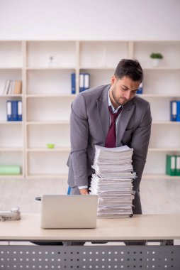 Young employee and too much work at workplace