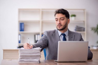 Young employee and too much work at workplace