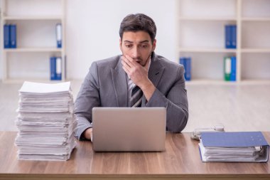 Genç bir çalışan ve ofiste çok fazla iş var.