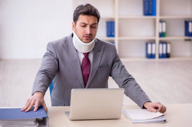 Young employee after car accident sitting at workplace
