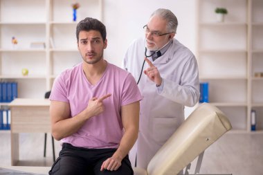 Genç hasta yaşlı doktoru ziyaret ediyor.