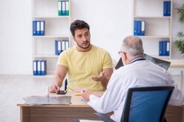 Genç hasta yaşlı doktoru ziyaret ediyor.