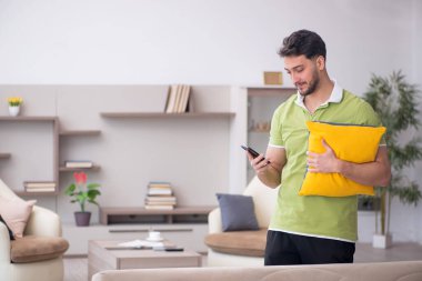 Evde bir sürü yastığı olan genç bir adam.