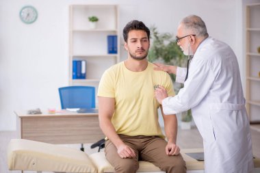 Genç hasta yaşlı doktoru ziyaret ediyor.