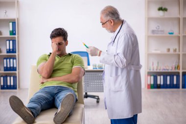 Genç hasta aşı konseptinde yaşlı doktoru ziyaret ediyor.