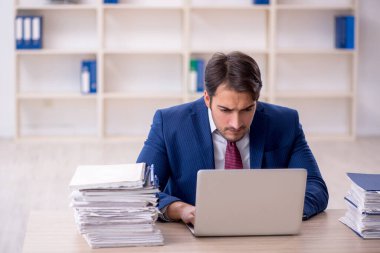 Genç işadamı ve işyerinde çok fazla iş var.