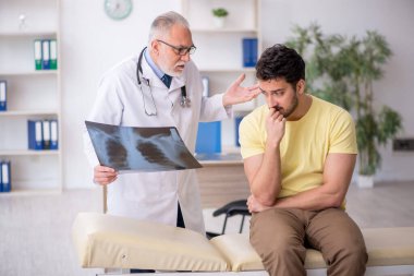 Genç hasta yaşlı doktoru ziyaret ediyor.