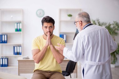 Genç hasta yaşlı doktoru ziyaret ediyor.