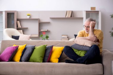 Evde bir sürü yastığı olan yaşlı bir adam.