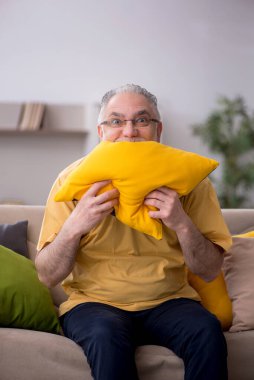 Evde bir sürü yastığı olan yaşlı bir adam.