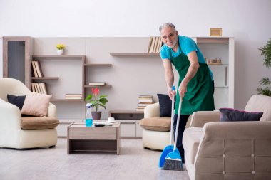 Yaşlı müteahhit evi temizliyor.