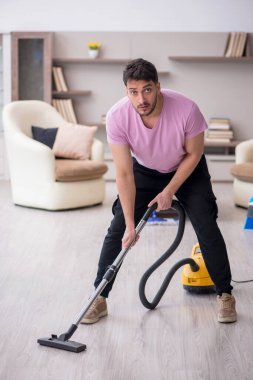 Genç müteahhit evi temizliyor.