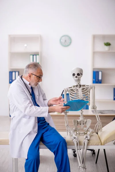 病院で骨格を調べる老医師 — ストック写真