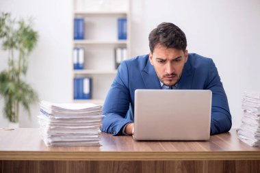 Young employee and too much work at workplace