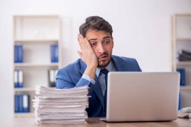 Young employee and too much work at workplace