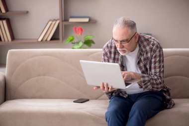 Yaşlı adam evde çalışıyor.