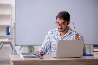 Genç öğretmen sınıfta oturuyor.