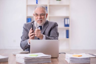 Old businessman employee unhappy with excessive work at workplace