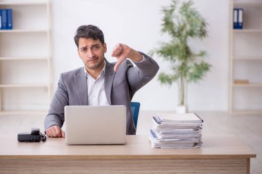 Young employee and too much work at workplace