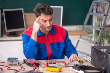 Sınıfta bilgisayar tamir eden genç bir tamirci.