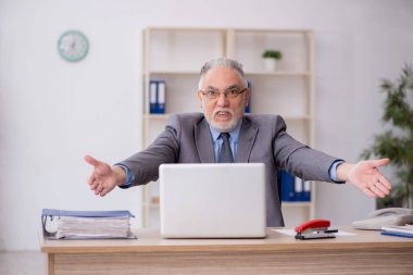 Old employee sitting at workplace