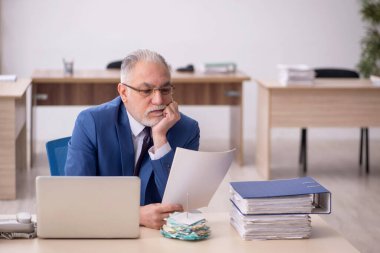 Old employee sitting at workplace