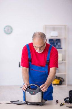 Yaşlı erkek tamirci atölyede sandviç tamircisi tamir ediyor.