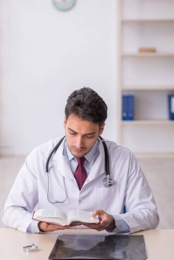 Hastanede kitap okuyan genç bir doktor.