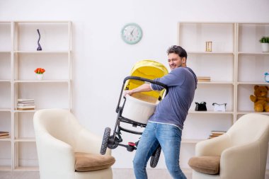 Genç erkek müteahhit evde yeni doğan bebeğe bakıyor.