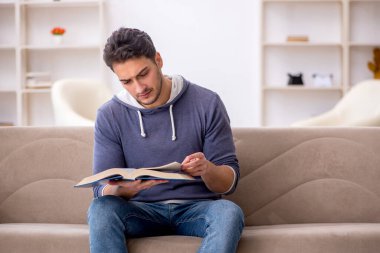 Evde kitap okuyan genç bir öğrenci.