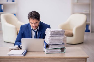 Young employee and too much work at workplace