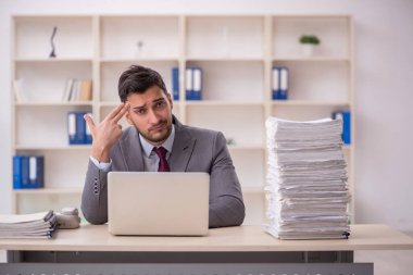 Young employee and too much work at workplace