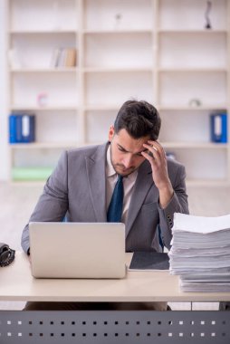 Young employee and too much work at workplace