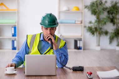 Genç mimar işyerinde oturuyor.