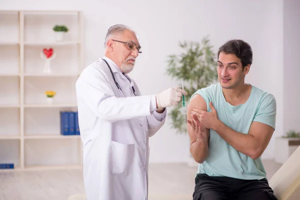 Genç Hasta Yaşlı Erkek Doktoru Aşı Konseptiyle Ziyaret Ediyor — Stok fotoğraf
