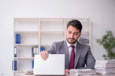 Young employee and too much work at workplace